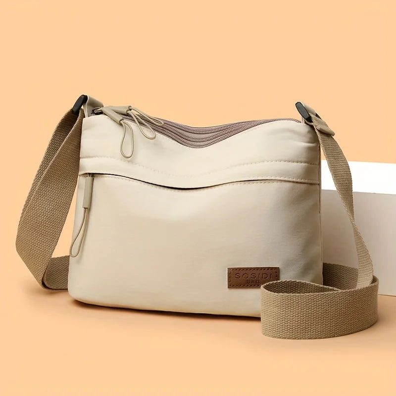 This large-capacity crossbody bag for women features a multi-zipper design and adjustable shoulder straps, making it suitable fo